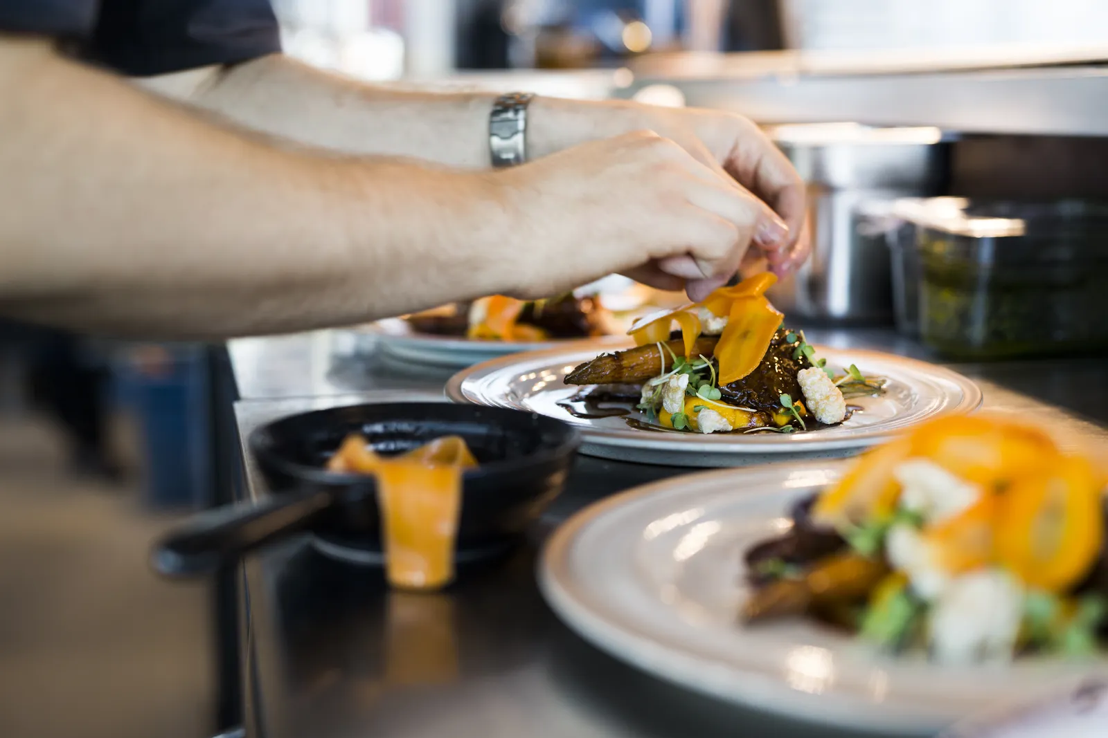 A chef plating a dish at the pass